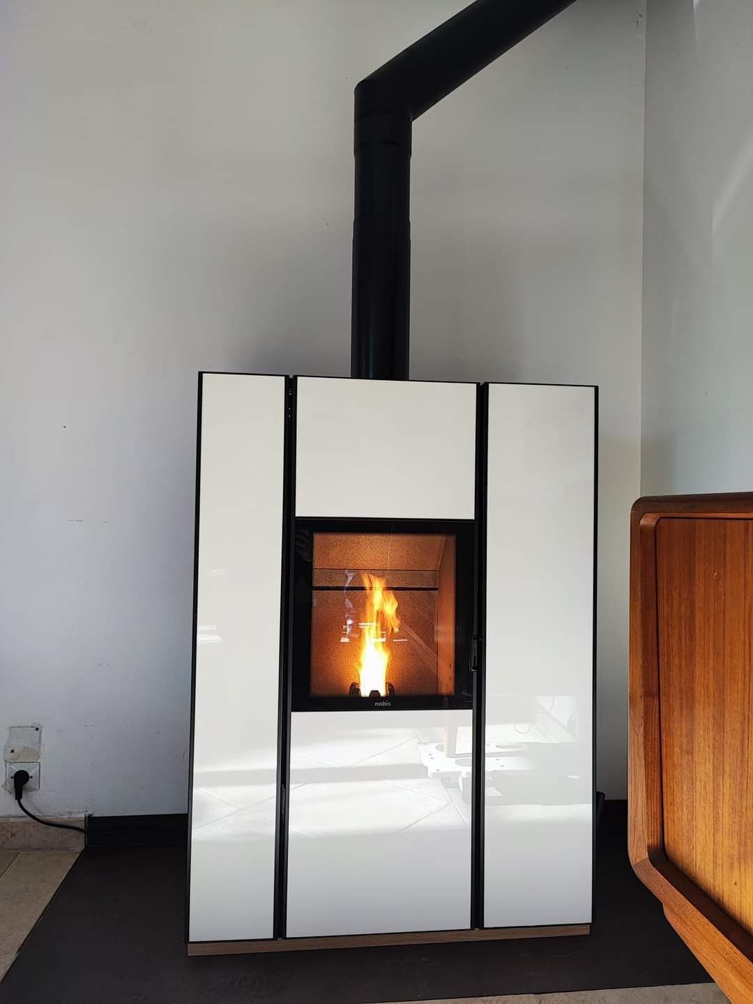 Poêle hybride Nobis UNICA à L’Isle-sur-la-Sorgue : finition en verre blanc ultra design, bois et granulés, autonomie en cas de coupure, allumage automatique et chauffage silencieux par convection naturelle.