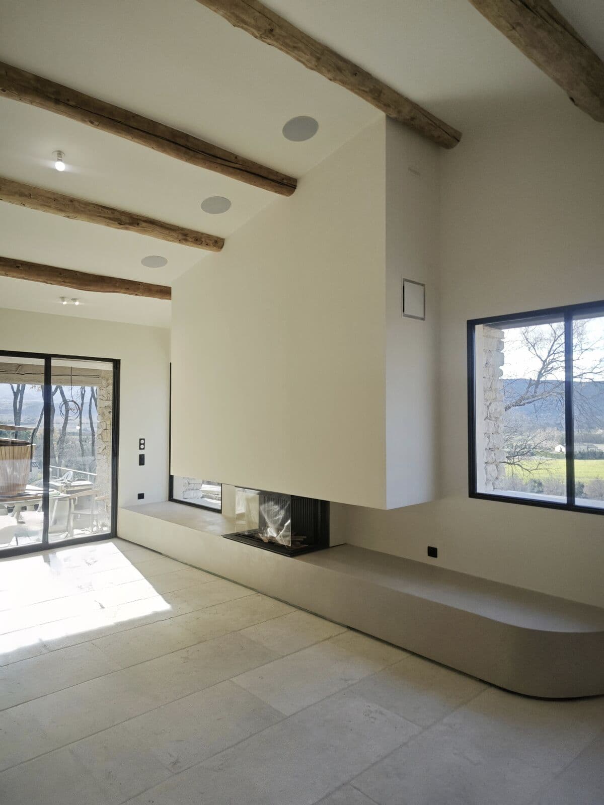 Cheminée à foyer design et contemporain vitrée 3 faces dans un intérieur moderne à Orange (84100) : design contemporain, banc maçonné sur mesure installé à Orange, 84100, par Flamme Concept dans le Vaucluse